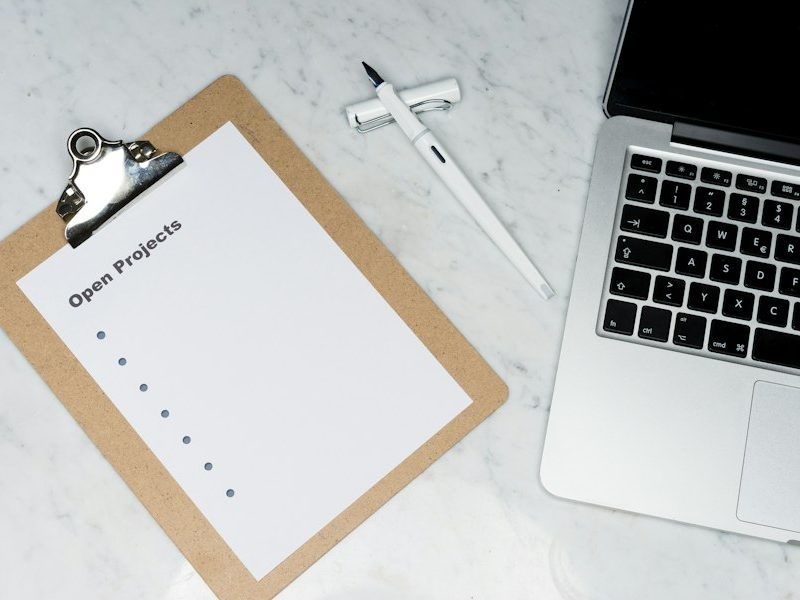 Tabla de apuntes con lista de verificación junto a un portátil